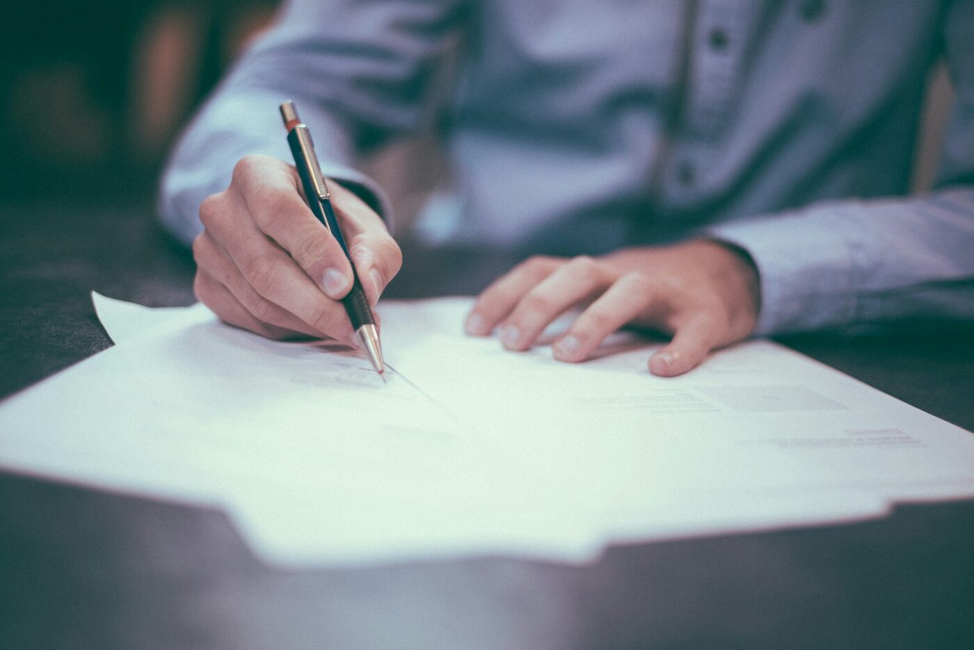 A client signing real estate documents at a notary's desk